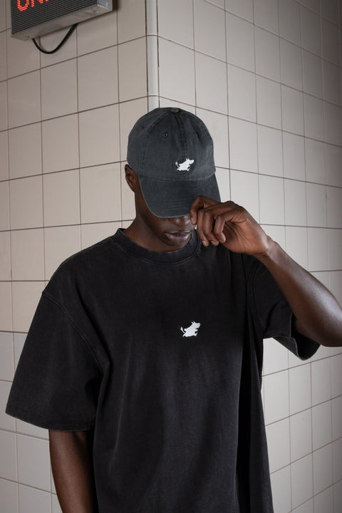 4. Man adjusting Moomin Classics Denim Dad Cap in dark grey, paired with matching t-shirt in lifestyle setting