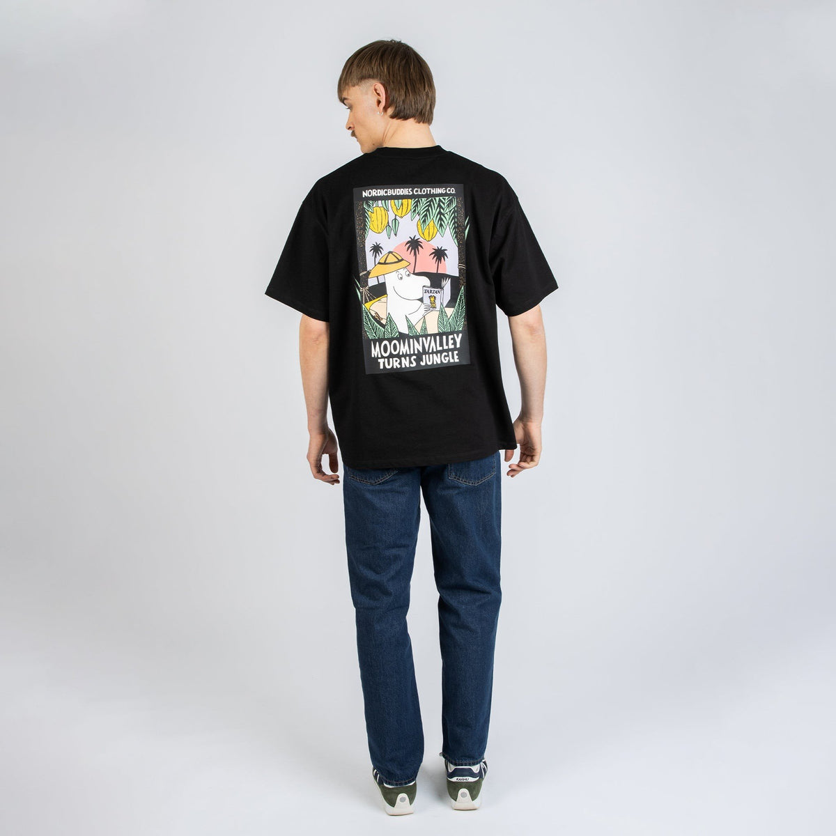 2. Female model wearing black Moomin Jungle t-shirt with small front logo, styled with jeans in studio