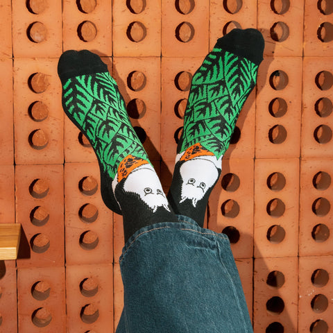 1. Men's Moomin Jungle retro socks in black with green leaf design, worn by model in casual setting