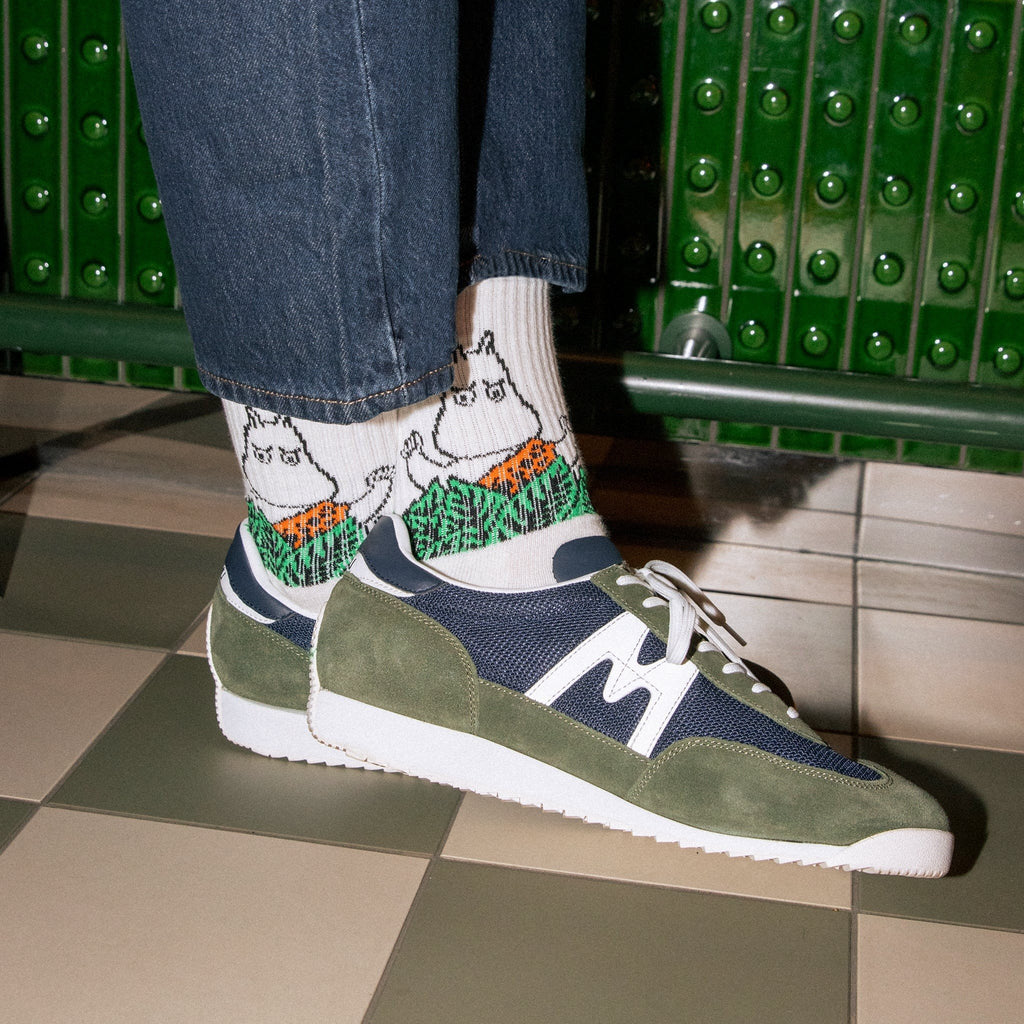 1. Men's Moomin Jungle retro socks in white worn with sneakers, showcasing playful jungle design in lifestyle setting