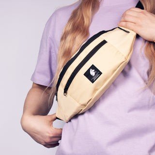 1. Woman wearing Moominpappa beige waist bag by NordicBuddies, showing adjustable strap and front pocket