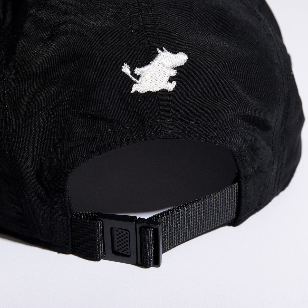 5. Close-up of adjustable strap and Moomintroll embroidery on black 5-panel cap
