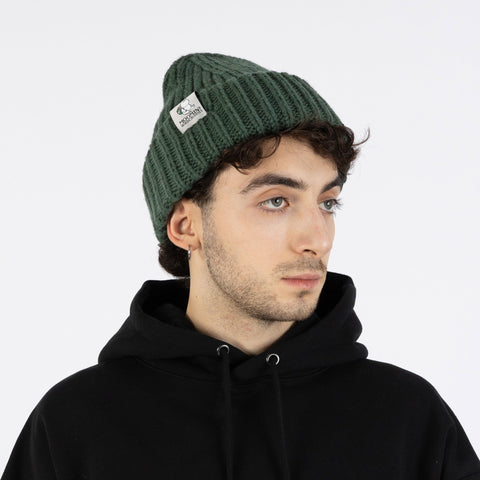 1. Man wearing green Moomintroll chunky beanie by NordicBuddies with black hoodie in studio setting