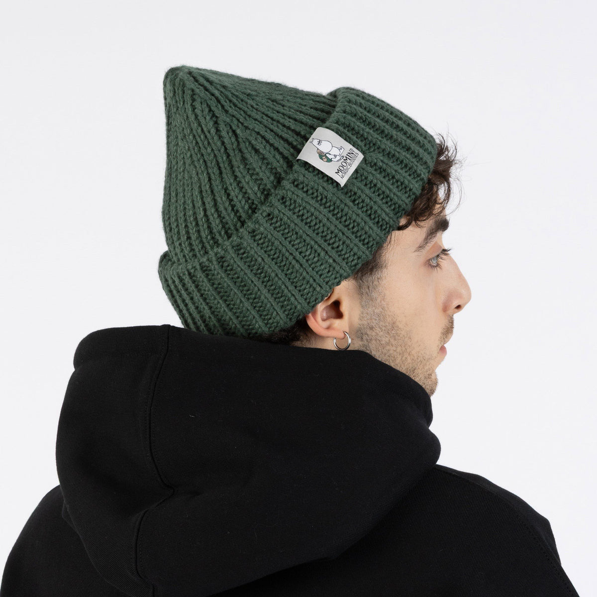 2. Side view of man wearing green Moomintroll chunky beanie by NordicBuddies with black hoodie