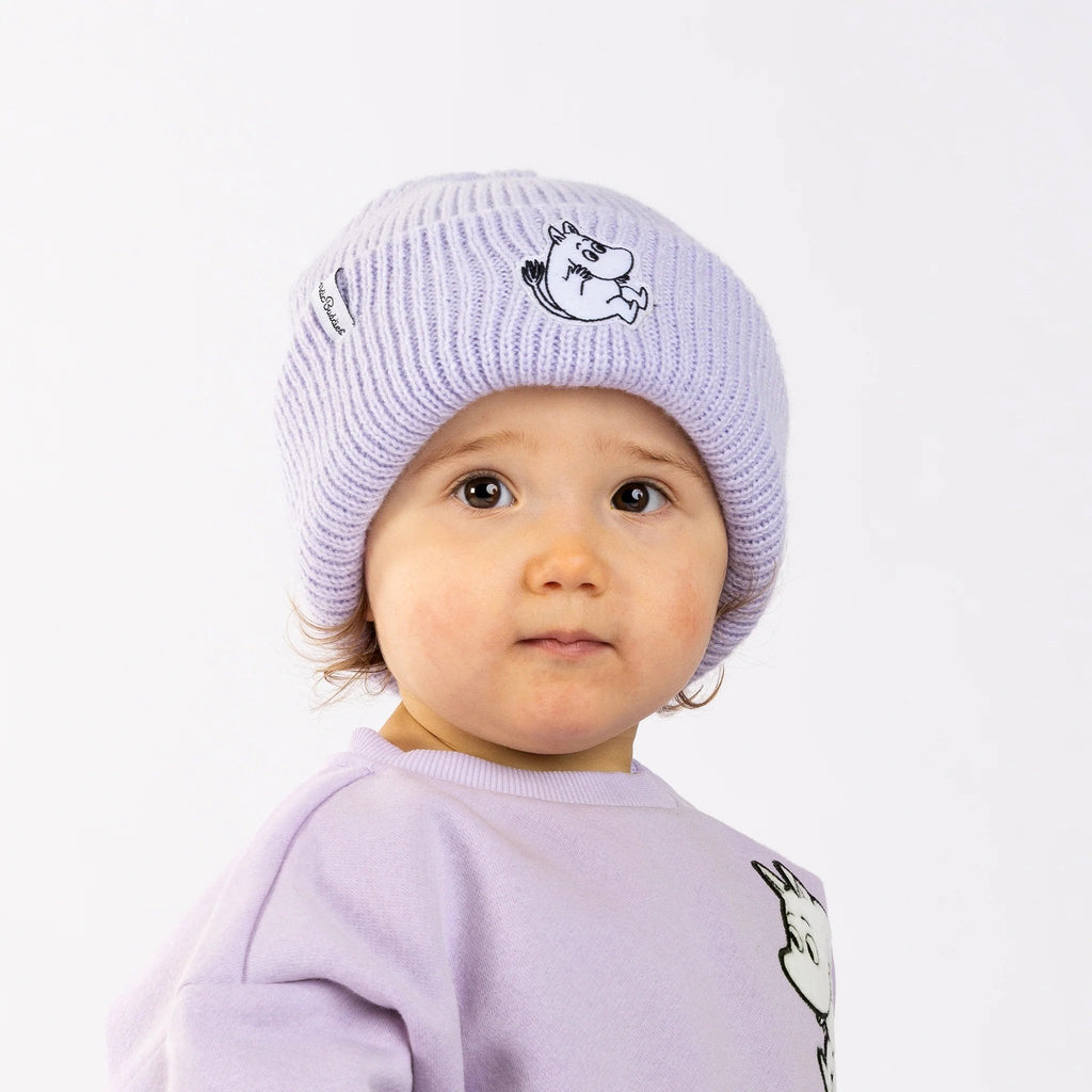 1. Child wearing lavender Moomintroll beanie with felt patch, smiling in studio setting