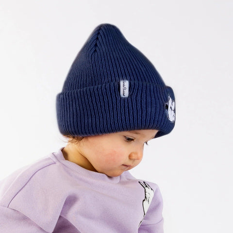 1. Child wearing navy Moomintroll beanie with felt patch and NordicBuddies logo, paired with a light purple top, against a white background