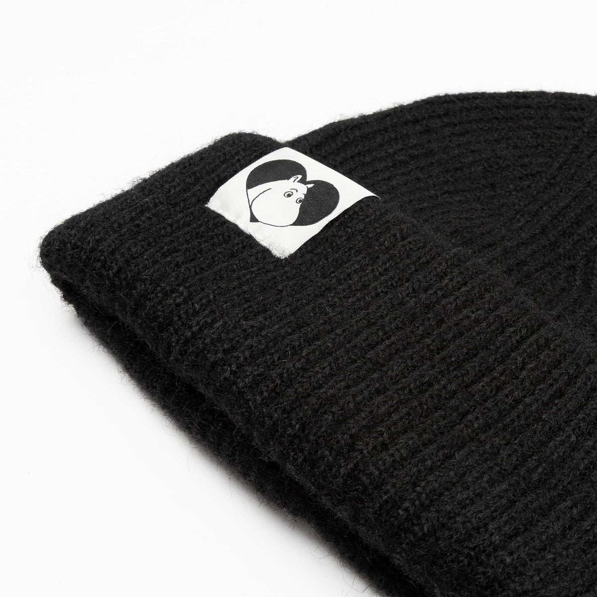 3. Close-up of black Moomintroll beanie showing logo detail on folded brim