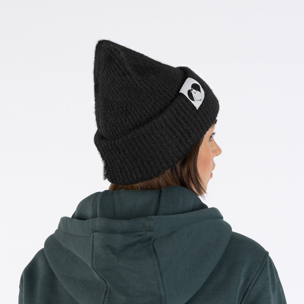 1. Woman wearing black Moomintroll beanie with logo, shown from back, in casual setting