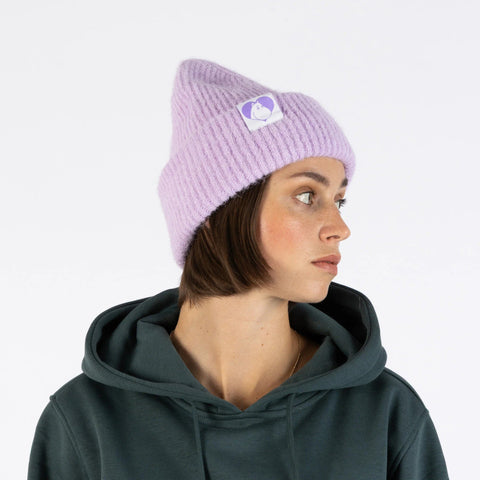1. Woman in lilac Moomintroll beanie with Moomin logo, looking sideways, wearing dark green hoodie