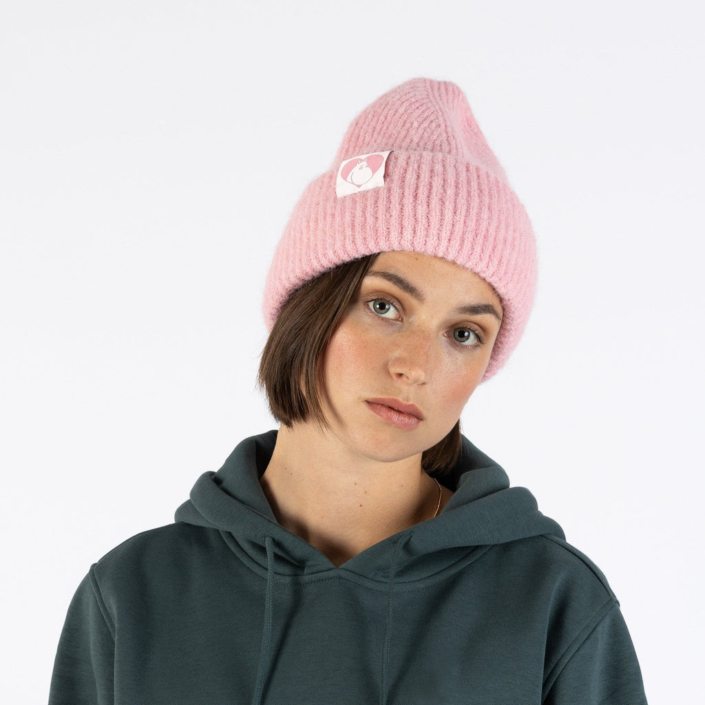 1. Woman wearing pink ribbed beanie with Moomin character patch, front view