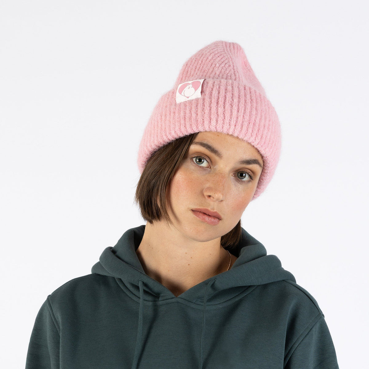 1. Woman wearing pink ribbed beanie with Moomin character patch, front view