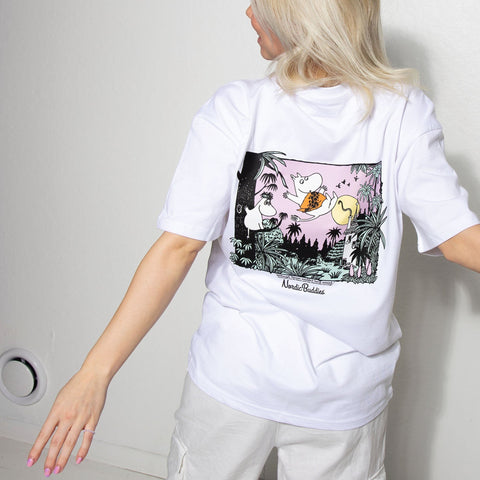 1. Woman wearing white Moomintroll Jungle unisex t-shirt with colorful back print, standing against a white wall