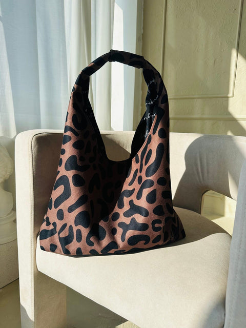 5. Garbanota Moon Bag in classic leopard print, placed on a beige chair in natural light