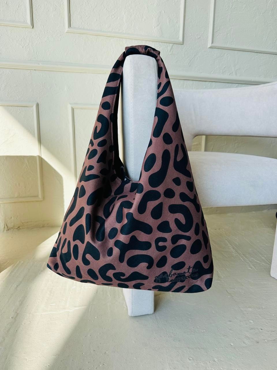 10. Garbanota Moon Bag in classic leopard print, shown on a white pedestal with natural lighting