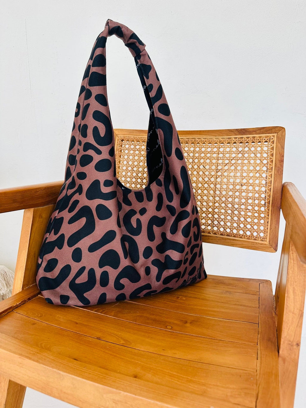 11. Garbanota Moon Bag in classic leopard print, placed on a beige chair with sunlight