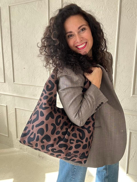 3. Woman showcasing Garbanota Moon Bag in classic leopard print, wearing a grey blazer and jeans