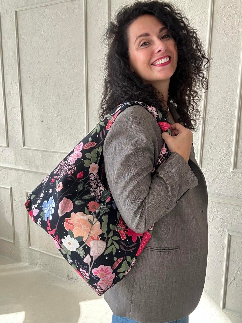 3. Woman wearing Garbanota Moon Bag - Curly Summer Night on shoulder, floral pattern, indoor setting