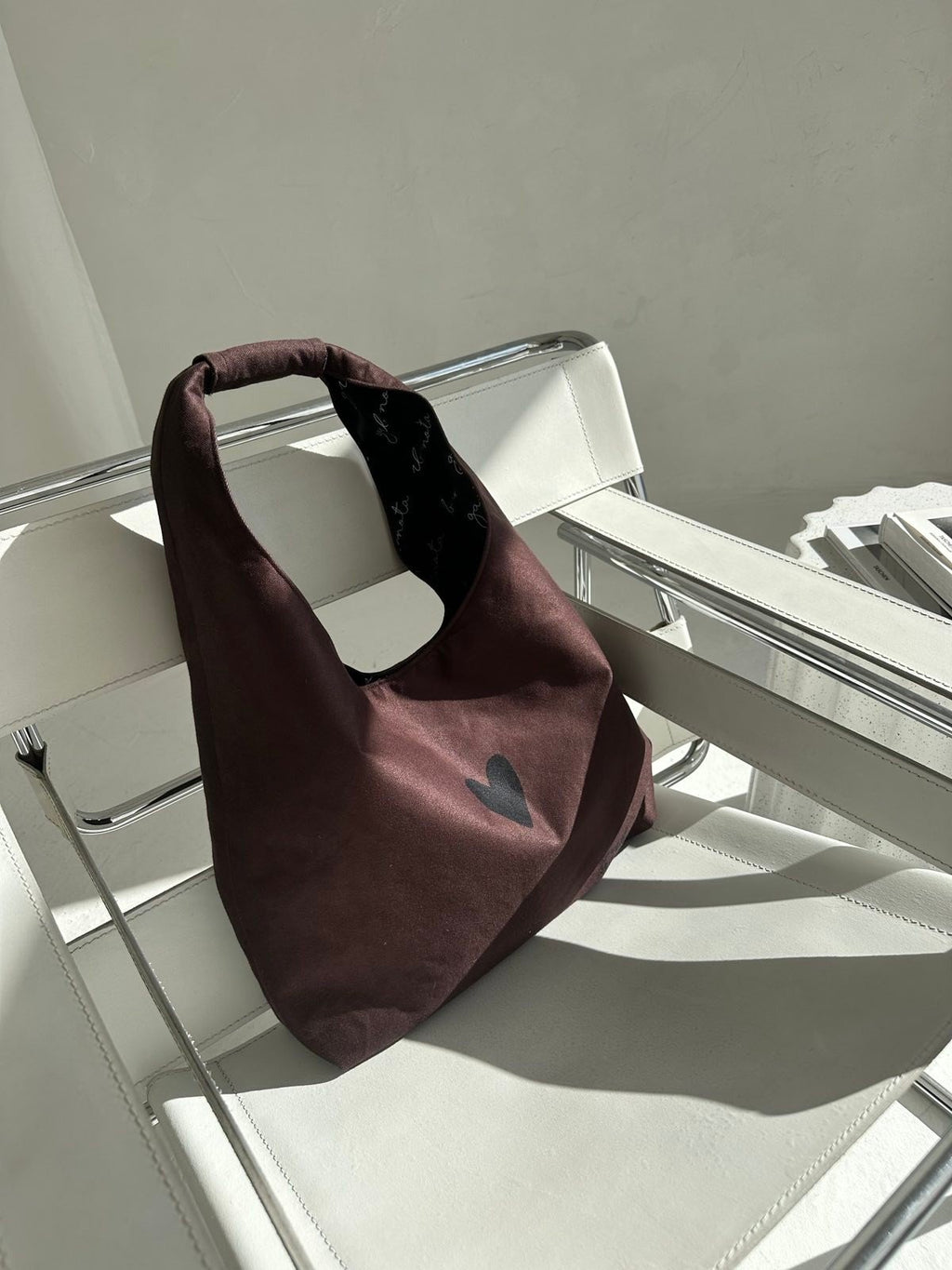 4. Garbanota Moon Bag Heart in brown on white chair, emphasizing heart design and lightweight material