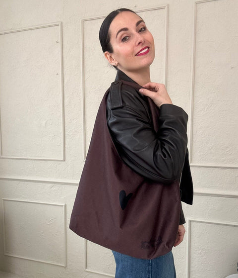 1. Woman wearing Garbanota Moon Bag Heart in brown, showcasing spacious design and heart detail