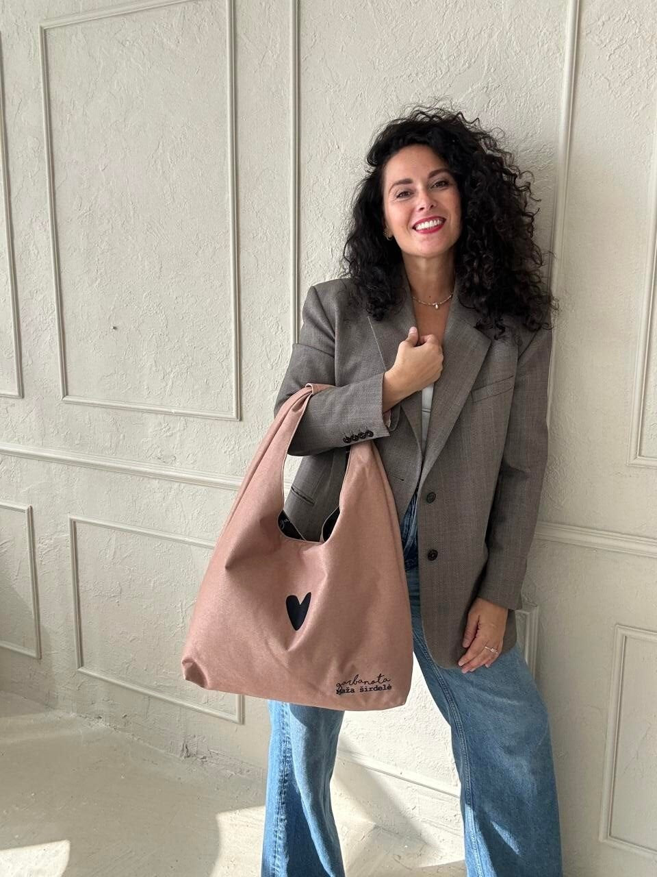 1. Woman holding Garbanota Moon Bag Heart in cream, styled with a blazer and jeans, lifestyle setting