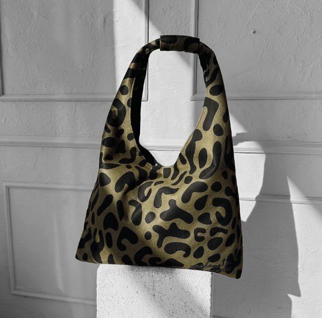 1. Garbanota Moon Bag Heart in khaki leopard print, shown in a lifestyle setting, highlighting its spacious design and unique style