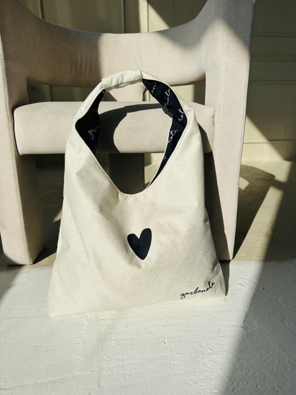 5. Garbanota Moon Bag Heart in white placed on a chair, highlighting soft canvas-like fabric