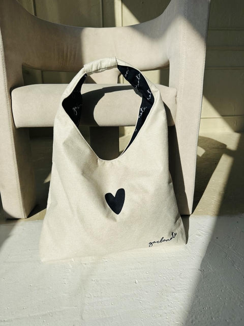 5. Garbanota Moon Bag Heart in white placed on a chair, highlighting soft canvas-like fabric