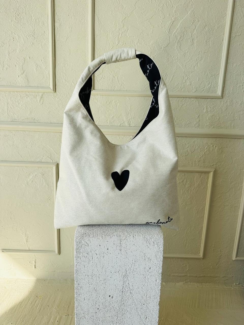 7. Garbanota Moon Bag Heart in white on a pedestal, emphasizing minimalist design