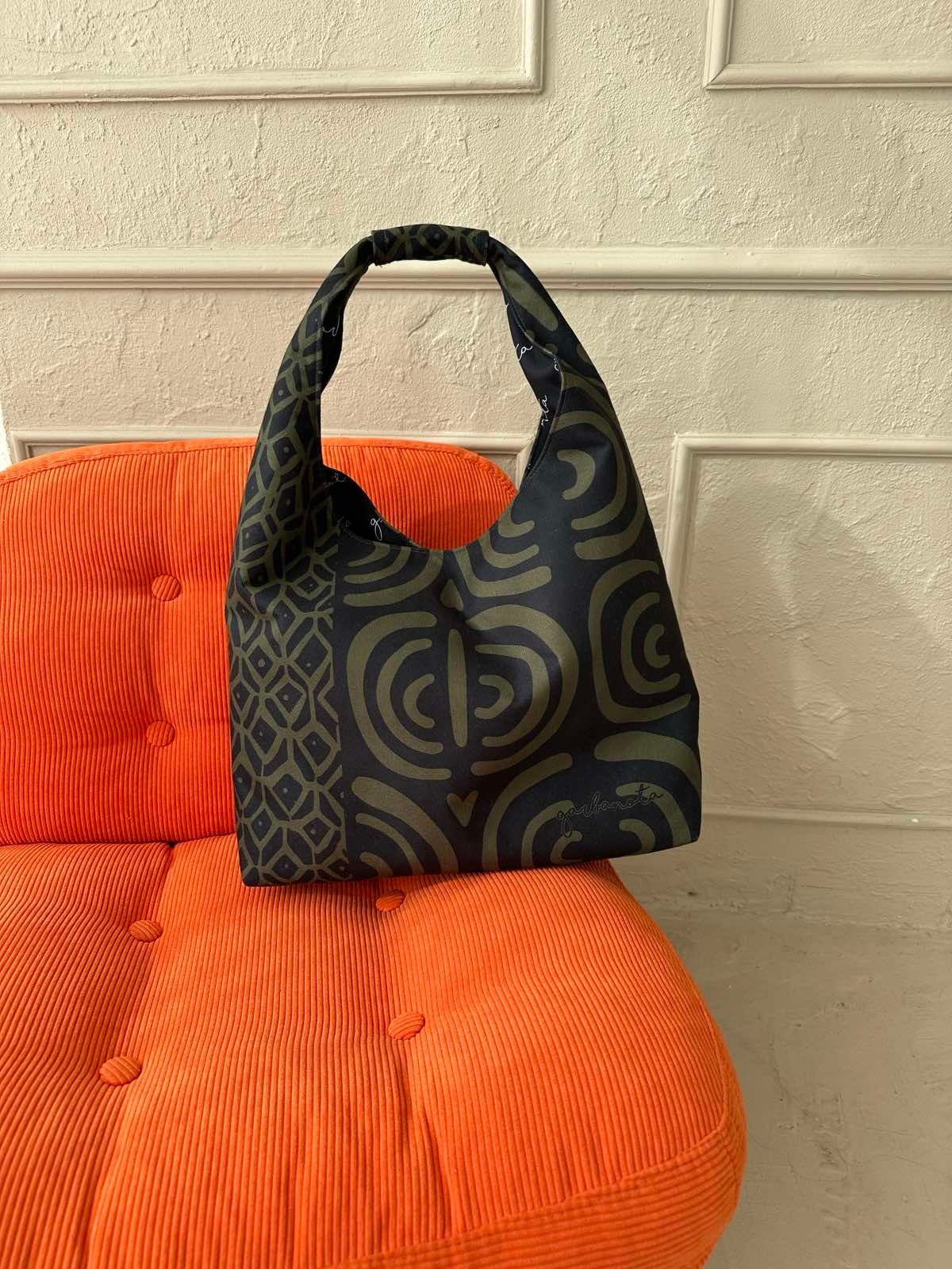3. Garbanota Moon Bag in khaki pattern on an orange chair, emphasizing bold style