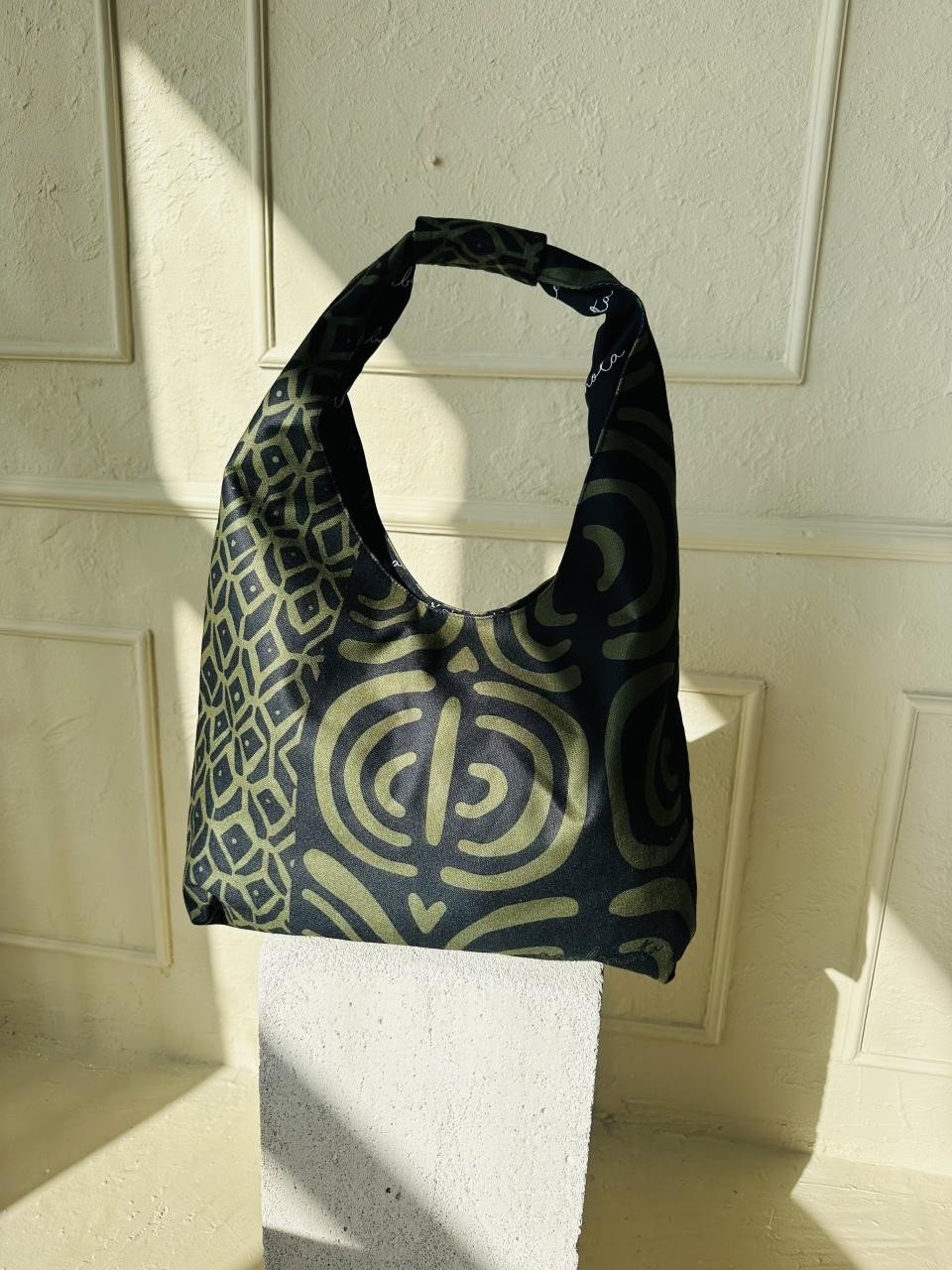 7. Garbanota Moon Bag in khaki pattern against a light wall, emphasizing craftsmanship