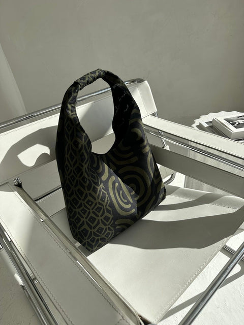 2. Garbanota Moon Bag in khaki pattern displayed on a white chair, highlighting unique design