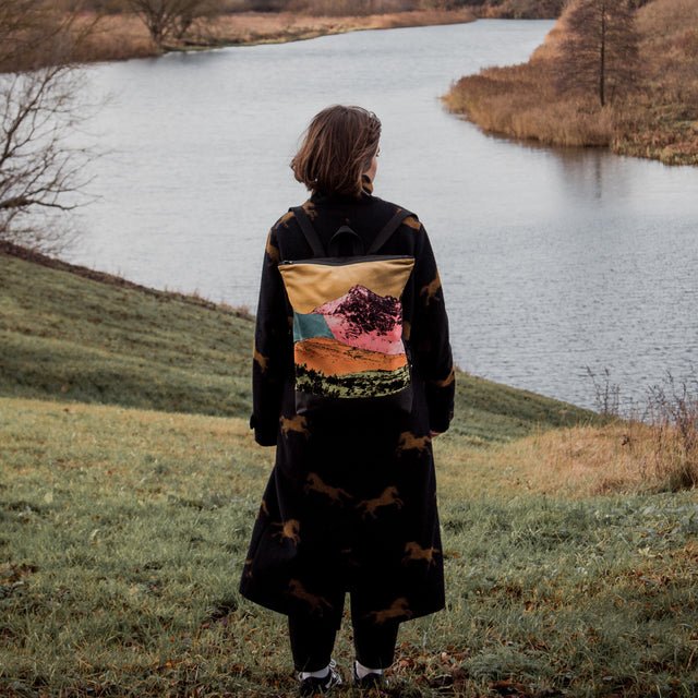 2. Woman standing by a lake with Muni Bold Mountains backpack, showing back view