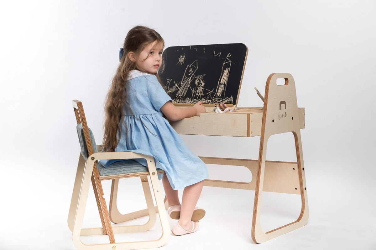 1. Girl in blue dress drawing on Luula Julle table with chalkboard in a studio setting