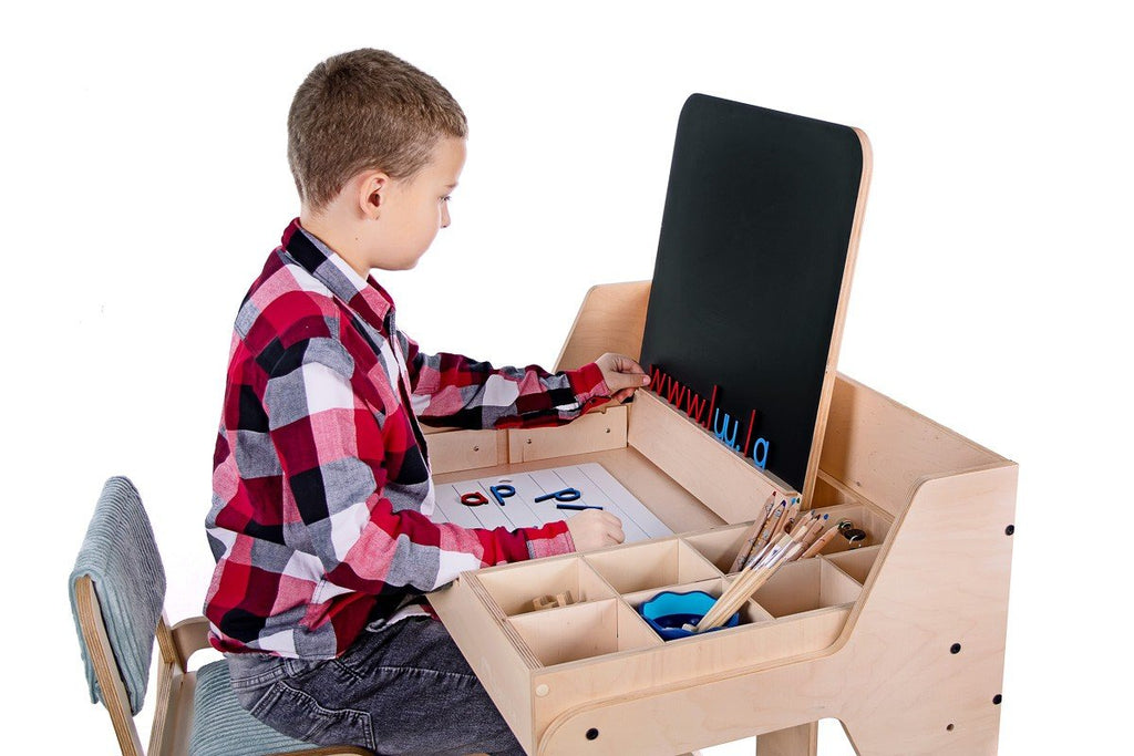 9. Boy using Luula table with chalkboard and storage compartments, highlighting educational play