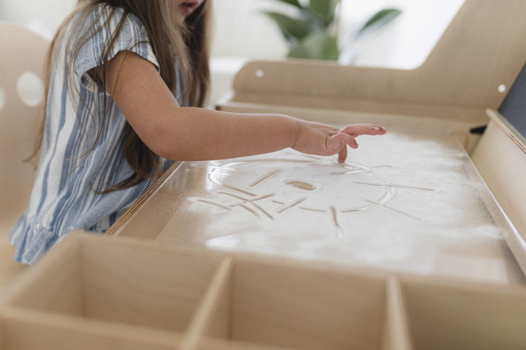 7. Child exploring textures on Luula table's surface, emphasizing sensory play and creativity