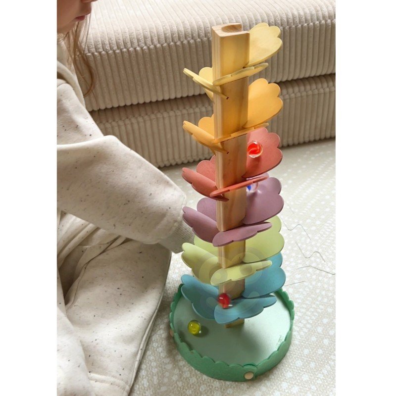 4. Close-up of child interacting with pastel rainbow wooden ball track on floor