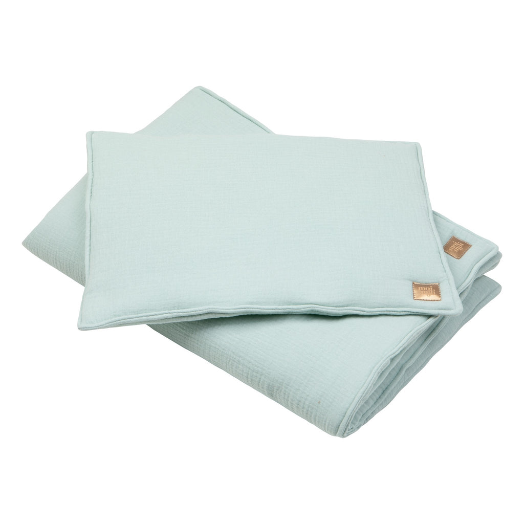 3. Close-up of mint muslin baby blanket and pillow set with sewn-in filling and brand tag