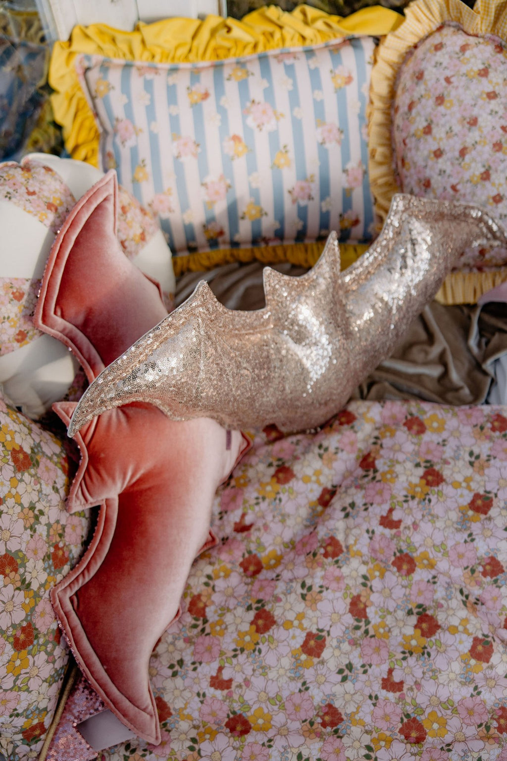 2. Muslin baby blanket with floral print in a cozy setting with decorative pillows and a glittery bat-shaped pillow