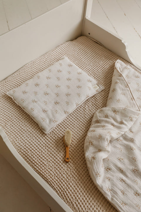 1. Muslin baby blanket and pillow set with boho flower print in a crib setting, accompanied by a baby brush on a textured beige mattress