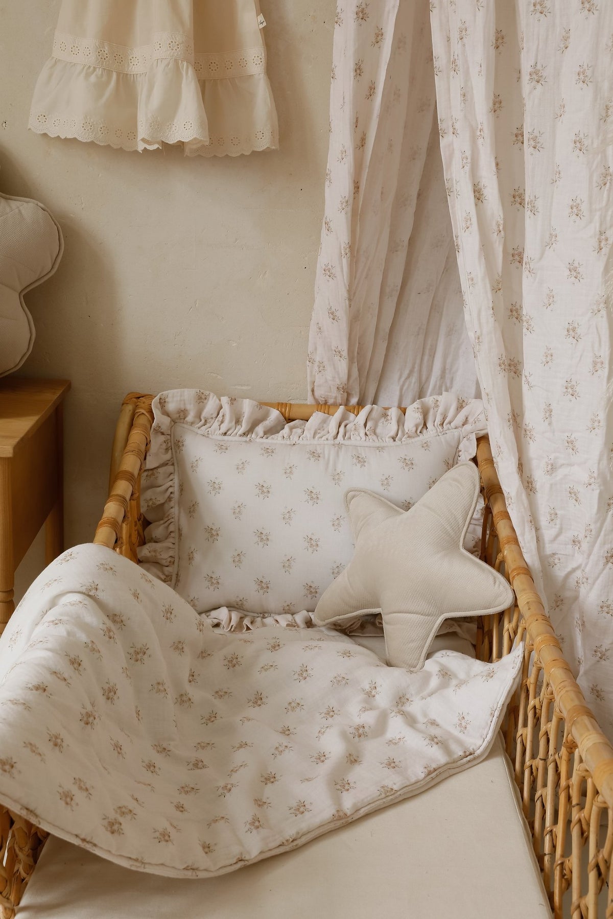 6. Muslin baby blanket and pillow set with boho flower print in a wicker crib, styled with a star-shaped cushion