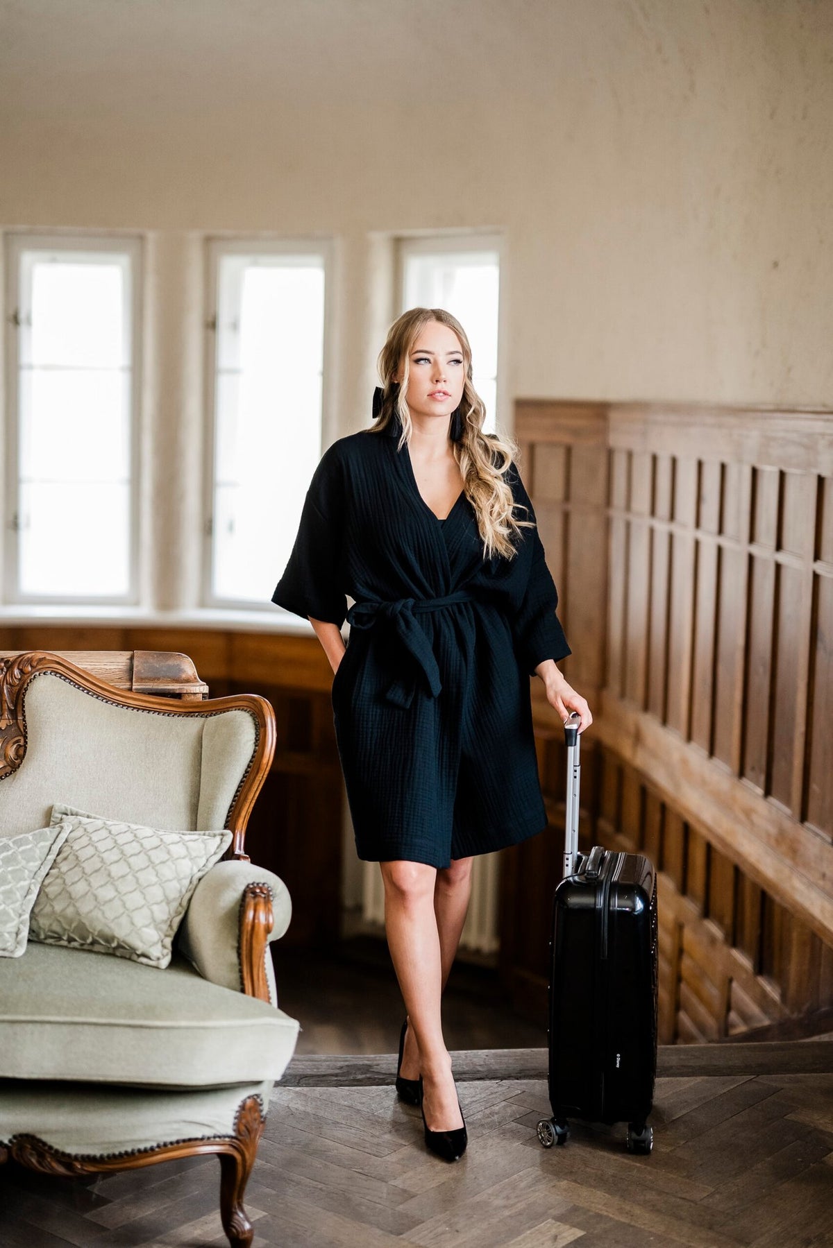 8. Women's black muslin kimono by RÄTT, worn by a model standing with a suitcase in a vintage room