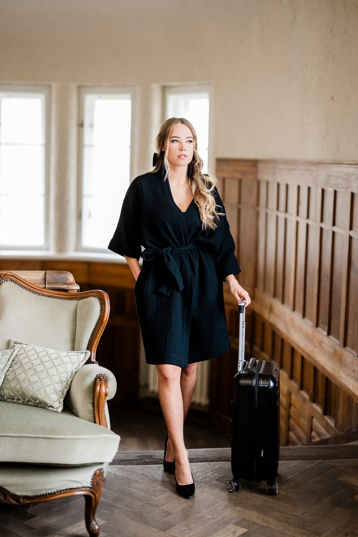 6. Women's black muslin kimono by RÄTT, worn by a model standing with a suitcase in a vintage room