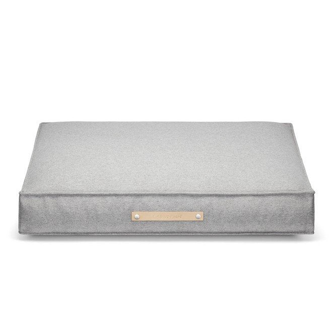 2. Grey Møvik dog cushion by Labbvenn with classic rectangular shape, featuring a leather belt with embossed logo on the front, shown in studio setting highlighting its minimalist design and durable fabric.