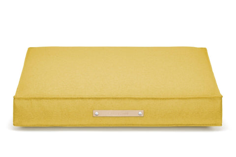 2. Labbvenn Møvik Cushion in honey color with leather belt and logo, shown in studio setting