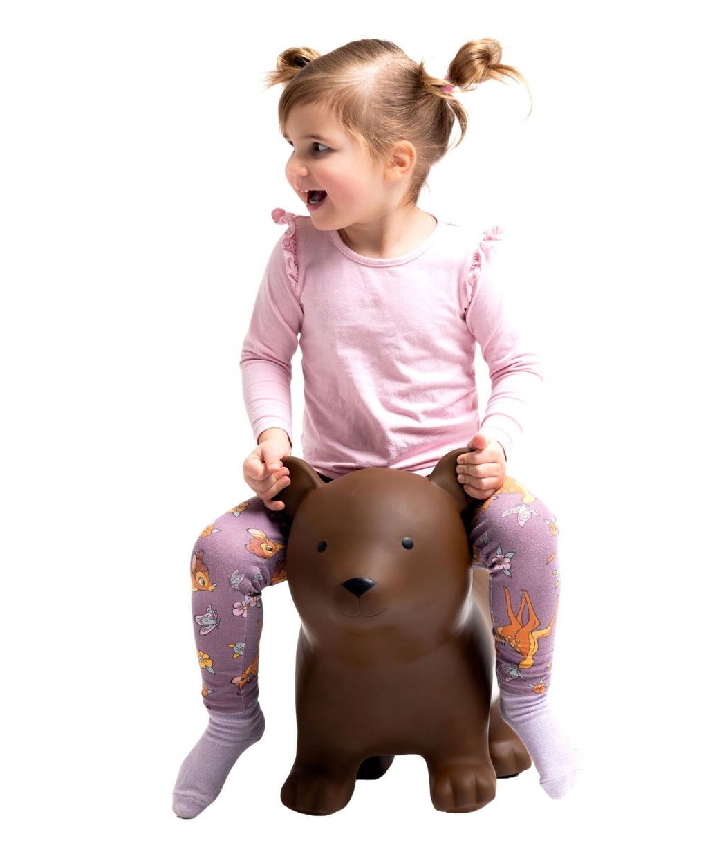 2. Child wearing pink shirt and colorful leggings excitedly riding Gerardo's Toys brown bear hopper in studio