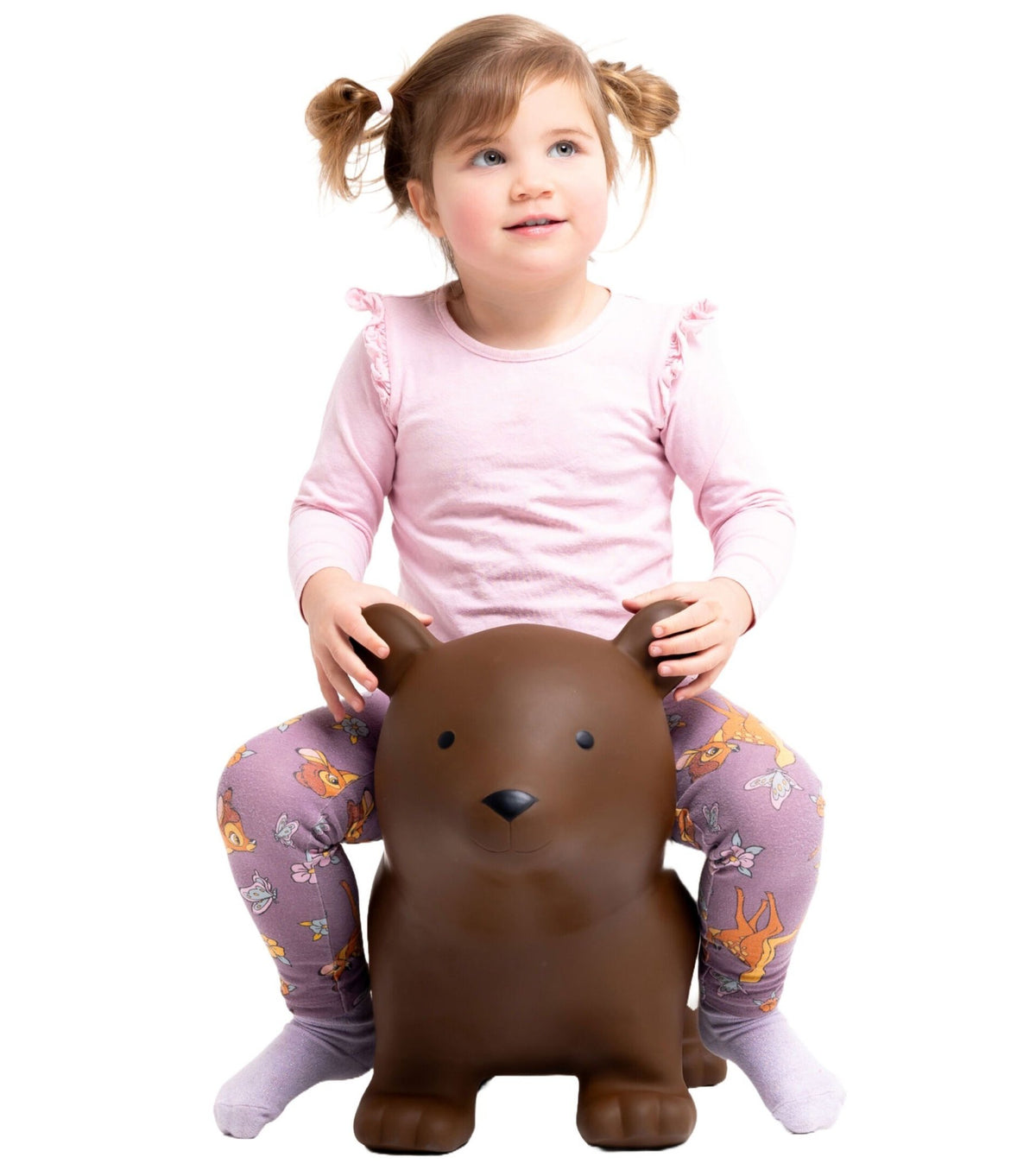 1. Young girl in pink top and patterned leggings sitting on Gerardo's Toys brown bear hopper, smiling in studio setting