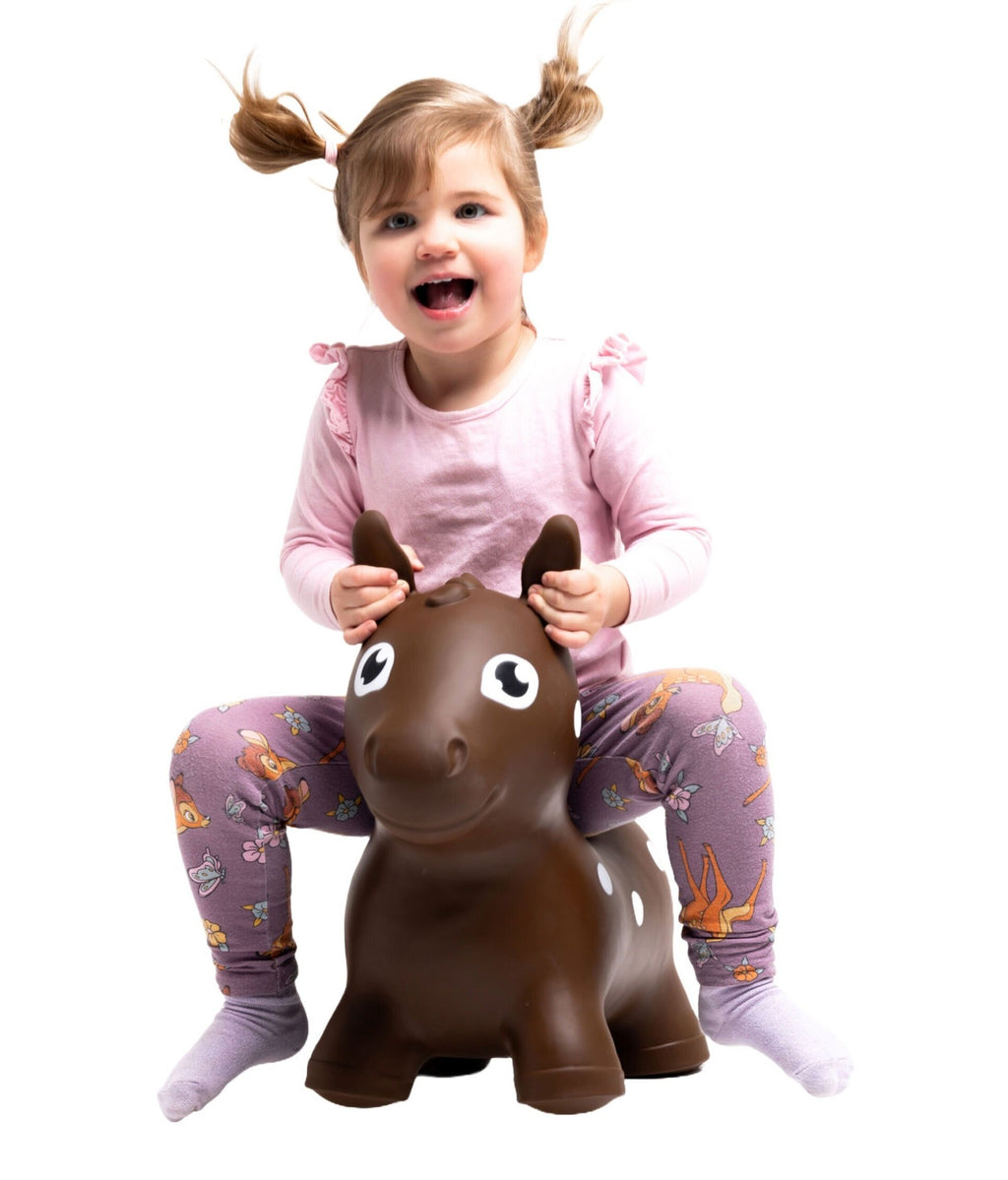 1. Girl in pink top and purple leggings sitting on brown horse hopper toy indoors