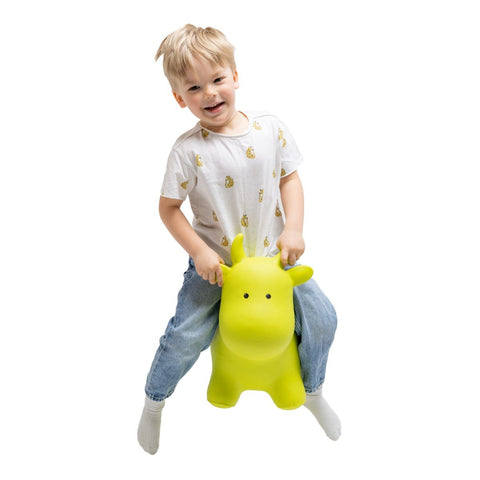 2. Smiling child bouncing on green cow hopper toy in white shirt and jeans