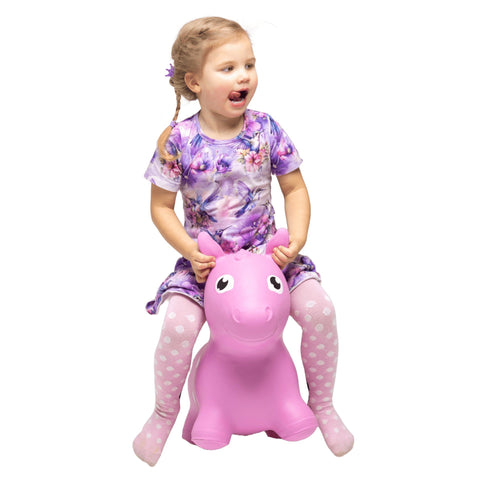 1. Young girl in a floral dress and polka dot tights riding a pink horse hopper toy indoors