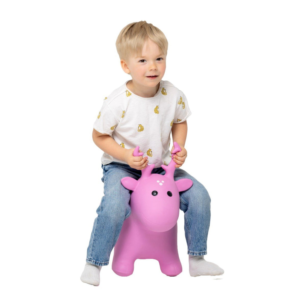 2. Boy in white t-shirt with yellow print and jeans sitting on pink moose hopper toy